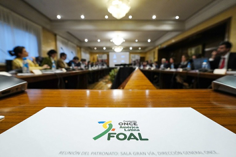 Logo de Foal en primer plano con la sala de Patronato como fondo difuminado