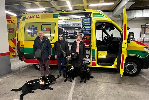 Usuarios de perro guía posan junto a una ambulancia