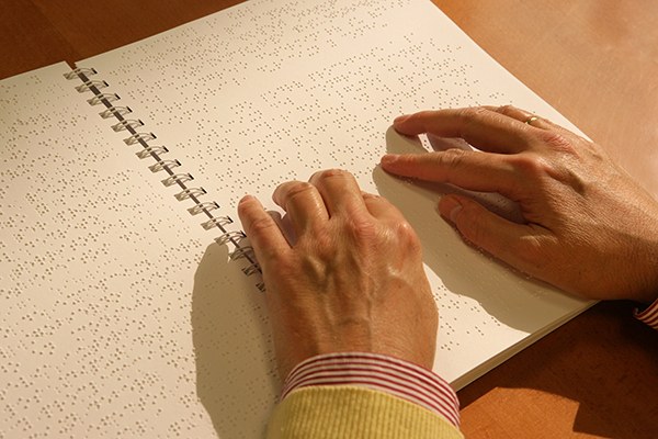 Manos de una persona afiliada leyendo braille