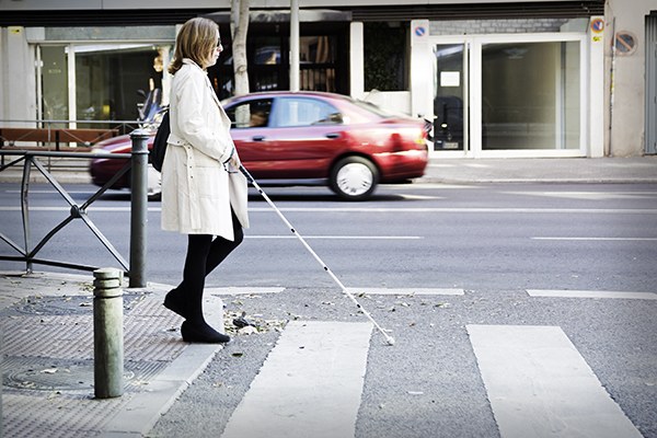 Una afiliada cruza la calle con su bastón