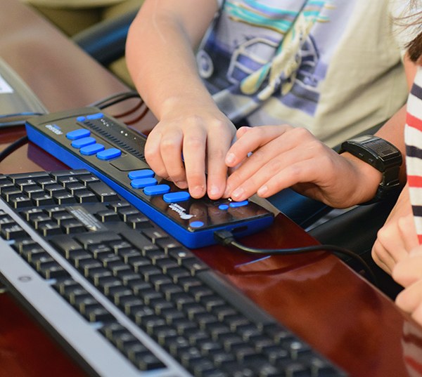 Manos de unos chavales utilizando tecnología adaptada