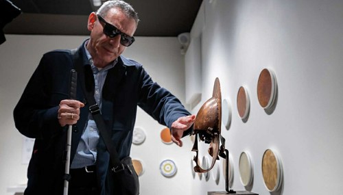 Una personas ciega toca las piezas del Museo