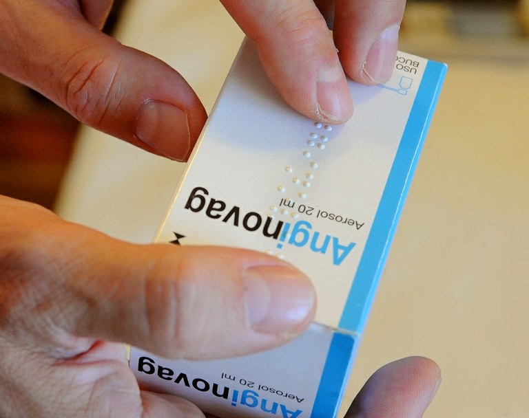 Manos tocando un medicamento etiquetado en Braille