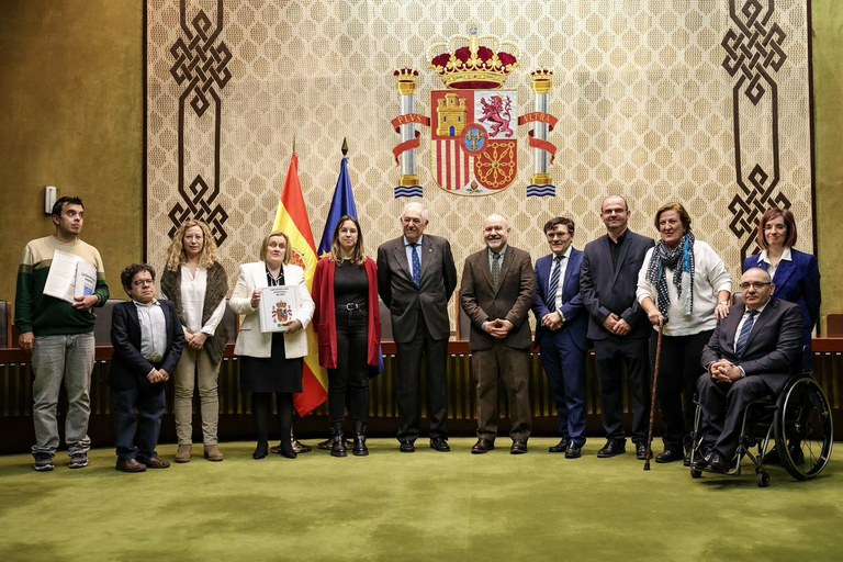 Foto de familia de los representantes del CERMI y Conde Pumpido mostrando los ejemplares accesibles de la Constitución