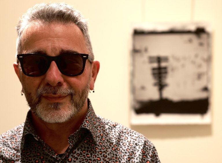 Primer plano de JM Magano en la exposición del Tiflológico con una de sus obras al fondo