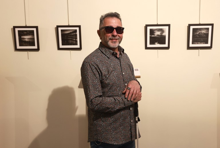 Magano posa junto a sus fotografías expuestas