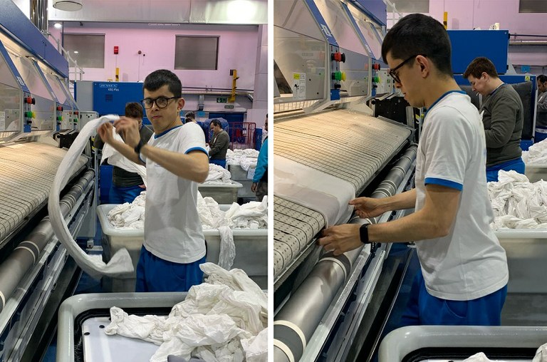 Daniel en su puesto de trabajo, metiendo sábanas en la planchadora