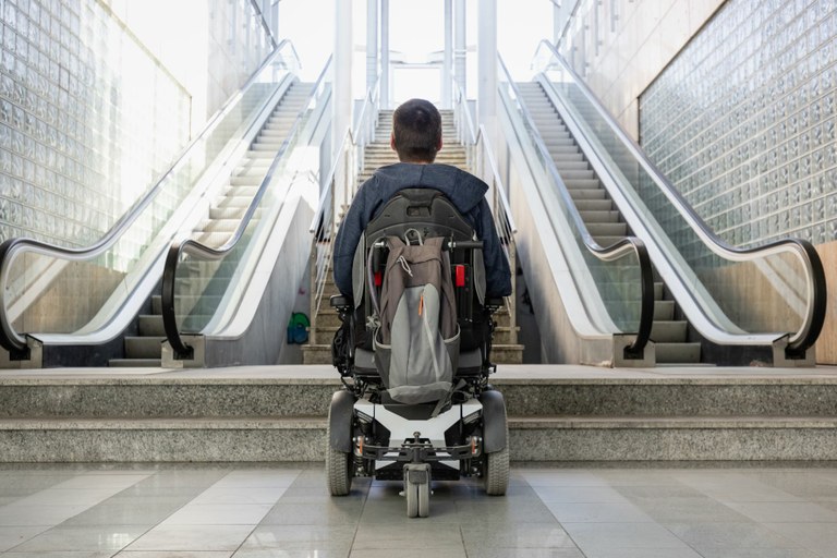 Persona en silla de ruedas frente a varias escaleras