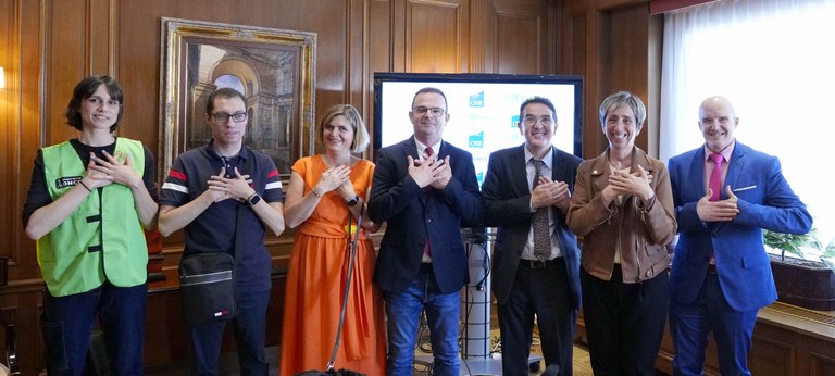 Responsables de la ONCE y CNSE, y personas sordociegas, en el acto de la firma del acuerdo para voluntariado. Todos los participantes hacen el signo del voluntariado