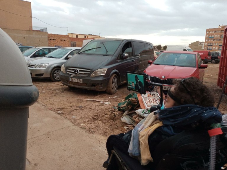 Persona con discapacidad afectada por la dana junto a unos automóviles Foto diario Levange El Mercantil Valenciano