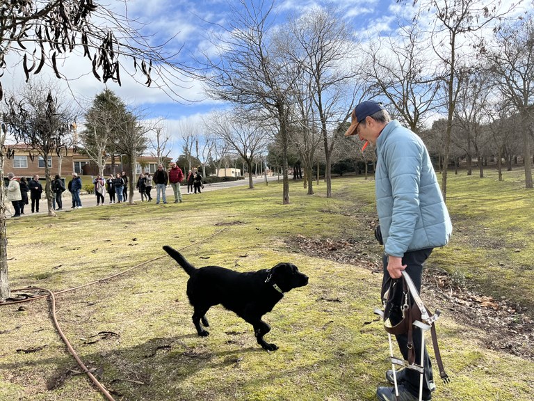 Sugus, futuro perro guía acudiendo a la llamada de Ricardo mientras explica a los voluntarios