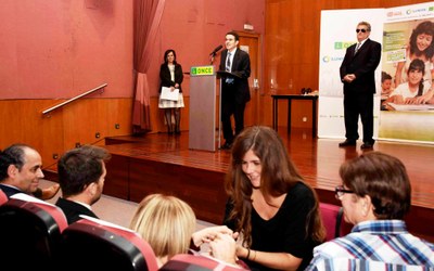 Andrés Ramos se dirige a los asistentes mientras la afiliada sordociega protagonista del programa de actuación recibe información gracias a su mediadora en primera fila