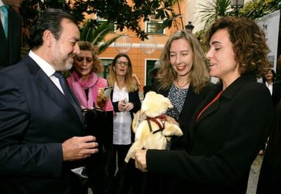 Al despedir a la ministra, el presidente de la ONCE le entrega un peluche de 'Fiel', la mascota perro guía de la FOPG