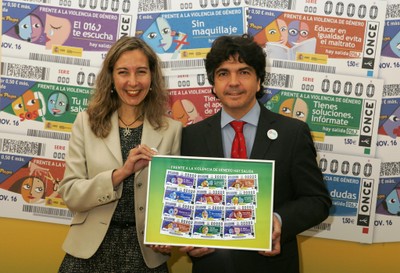 Patricia Sanz y Mario Garcés posan con la reproducción de la colección de cupones sobre violencia de género