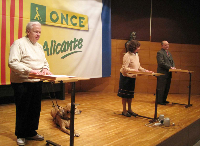 Miembros del grupo “Tomás Aznar” proceden a la lectura en braille de una serie de relatos en el  acto celebrado en Alicante con motivo del Día Mundial del Braille 2013