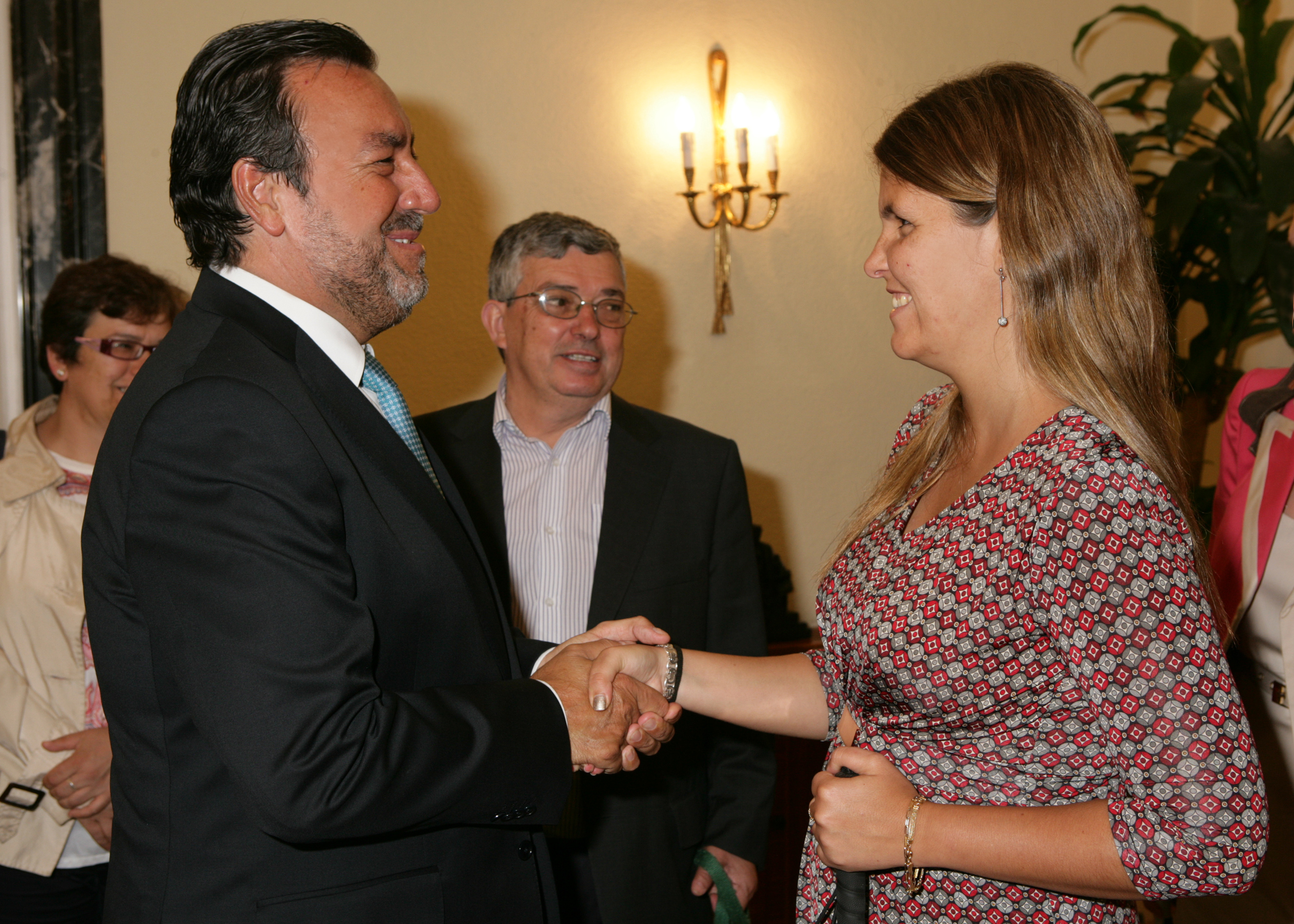 Miguel Carballeda (izquierda) saluda a Ana Sofía Antunes a su llegada al Consejo General de la ONCE. En el centro, Augusto Hortas, tesorero de ACAPO.