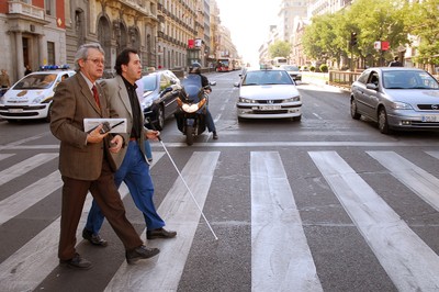 Un voluntario ayundando en la movilidad y seguridad de un joven afiliado para cruzar una calle