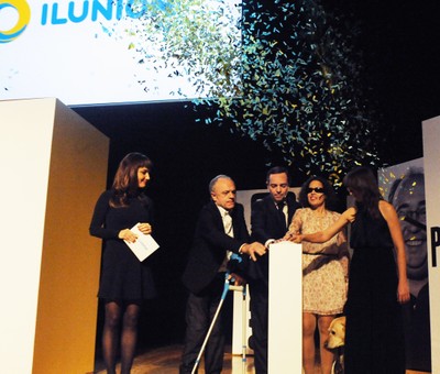 Un grupo de trabajadores de ILUNION hacen volar una lluvia de confeti sobre el escenario en el acto inaugural
