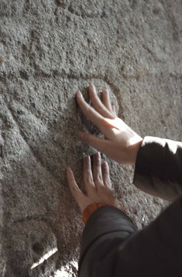 Detalle de una persona reconociendo al tacto un grabado natural en piedra en un muro de la "Ruta del Mejillón" de Arousa 
