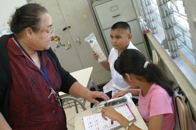 Niños de la escuela salvadoreña recibiendo el material donado desde España de manos de una de sus profesoras