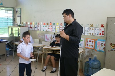 Aula con niños, junto a un profesor, de la escuela "Eugenia Dueñas" de El Salvador, mostrando los bastones blancos recibidos desde España