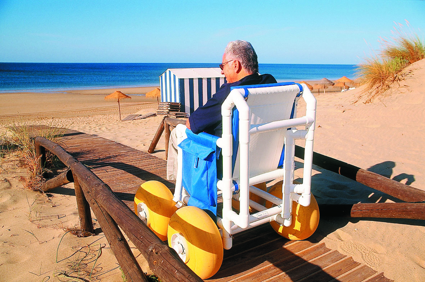 Un turista con discapacidad física utiliza un sendero de desplazamiento para silla de ruedas en una playa