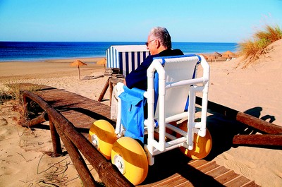 Un turista con discapacidad física utiliza un sendero de desplazamiento para silla de ruedas en una playa