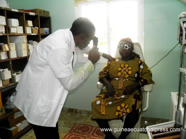 Un oftalmólogo local efectúa una revisión visual a una mujer guineana 