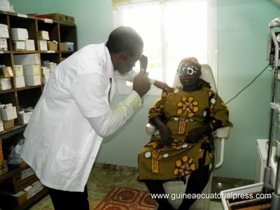 Un oftalmólogo local efectúa una revisión visual a una mujer guineana 