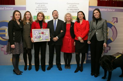 Susana Camarero sostiene el cartel con los cupones dedicados a la Igualdad Salarial y al Día Internacional de la Mujer, flanqueada por Patricia Sanz, Miguel Carballeda y Reyes Lluch, además de otras responsables institucionales invitadas al acto