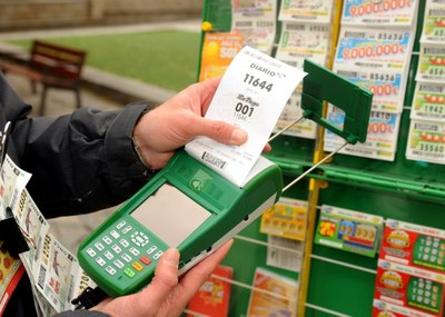 Las manos de un vendedor imprimiendo un cupón diario en su TPV