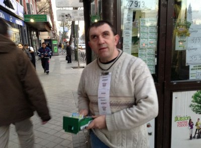 Marcelino Monguía expendiendo un producto por TPV. a las puertas de su quiosco en Madrid
