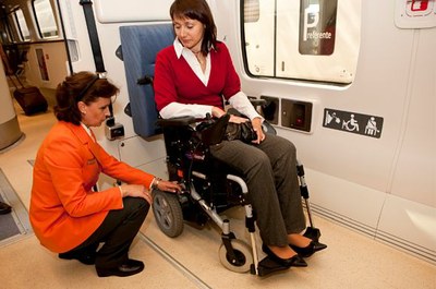 Una auxilliar del servicio Atendo ayuda a una viajera a anclar su silla de ruedas a bordo del tren
