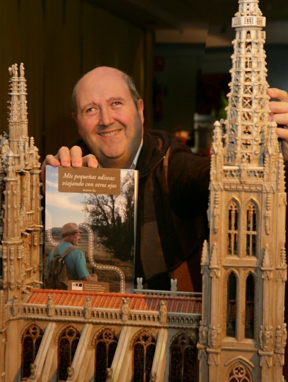 Alberto Gil posa con su libro-guía de viajes 'Mis pequeñas odiseas: viajando con otros ojos', mientras sus dedos recorren la maqueta de la Catedral de Burgos, en el Museo Tiflológico de la ONCE