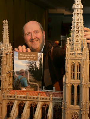 Alberto Gil posa con su libro-guía de viajes 'Mis pequeñas odiseas: viajando con otros ojos', mientras sus dedos recorren la maqueta de la Catedral de Burgos, en el Museo Tiflológico de la ONCE