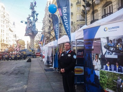 Un vigilante de ILUNION Facility Services junto a la carpa instalada por la empresa en pleno centro de Valencia durante las Fallas