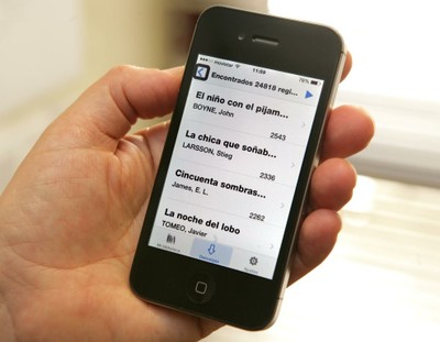 Imagen de la mano de un usuario con su smartphone con la aplicación GOLD abierta y un listado de obras literarias para descargar
