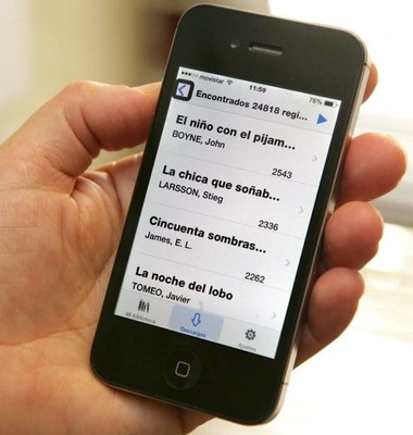 mano de un usuario con su smartphone con la aplicación GOLD abierta y un listado de obras literarias para descargar  