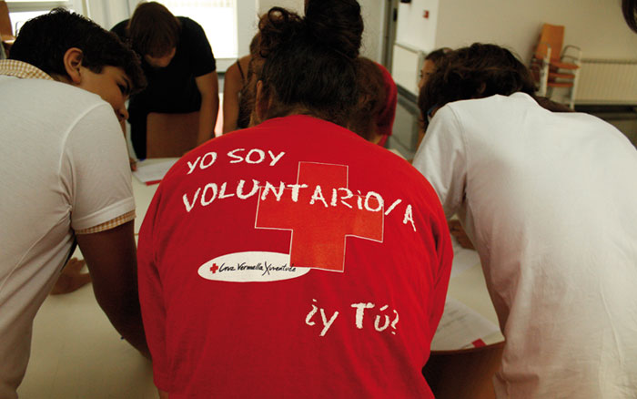 Reunión de un grupo de voluntarios de Cruz Roja, una de ellas con una camiseta con el eslogan "Yo soy voluntario/a. ¿Y tú?"