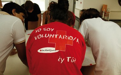Reunión de un grupo de voluntarios de Cruz Roja, una de ellas con una camiseta con el eslogan "Yo soy voluntario/a. ¿Y tú?"