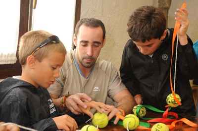 Un par de chavales con discapacidad visual aprenden, junto a su instructor, a realizar una manualidad con pelotas de tenis en los campamentos del año pasado