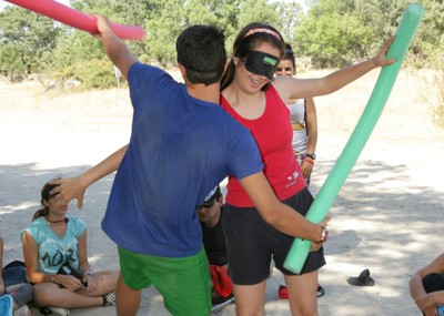 Dos jóvenes con antifaz realizando un juego en el campamento madrileño de NaturEscorial