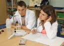 Dos de los escolares toman notas mientras observan atentamente una reacción física