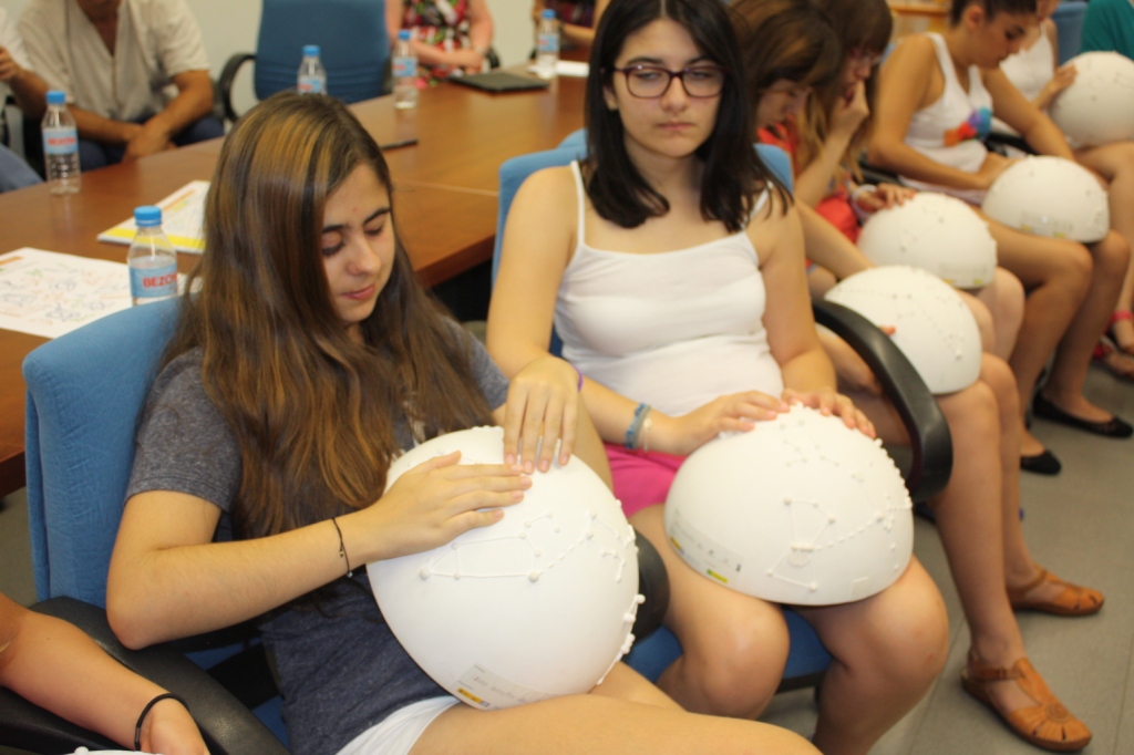 Un grupo de alumnas reconociendo al tacto la disposición de las galaxias utilizando unas semiesferas con información en relieve