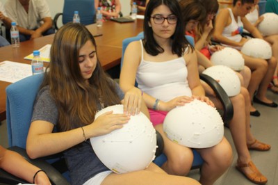 Un grupo de alumnas reconociendo al tacto la disposición de las galaxias utilizando unas semiesferas con información en relieve