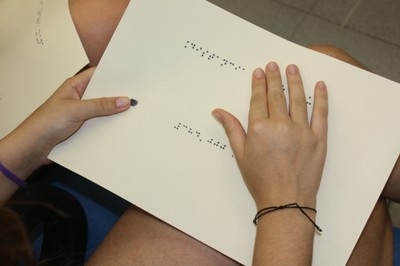 Una alumna consulta una ficha de trabajo en braille