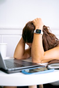 Chica inclinada sobre ordenador portátil sujetándose la cabeza con las manos